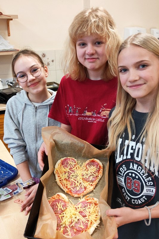 Dziewczynki wstawiają do piekarnika swoje sercowe pizze