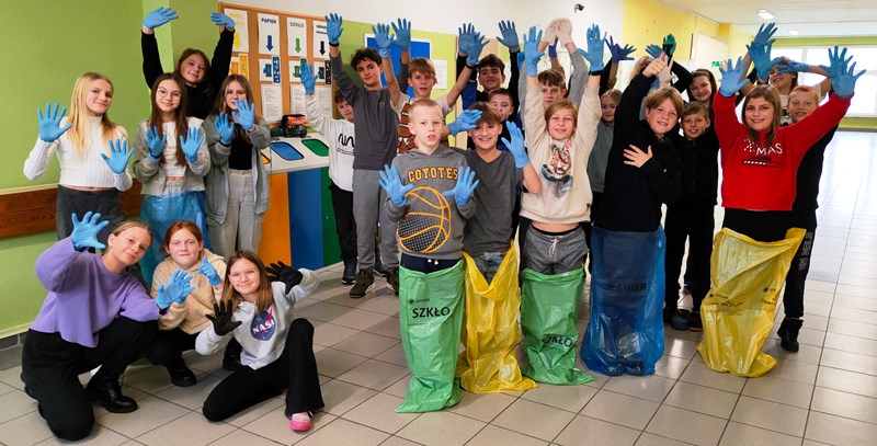 Uczniowie klasy 5a w gumowych rękawiczkach, z workami na śmieci, przygotowani do akcji sprzątania lasu