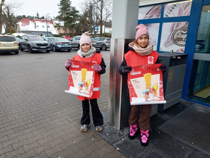 Dwie wolontariuszki z plakatami przed wejściem do sklepu Lidl.