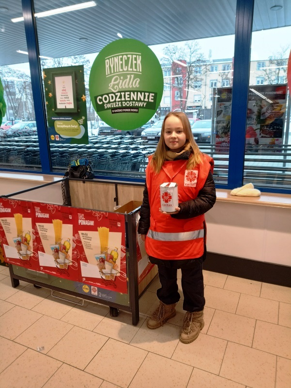 Wolontariuszka stoi z puszką Caritas w sklepie Lidl