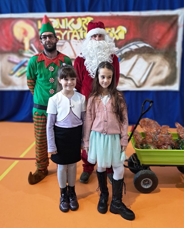Marta i Zuzia pozują do zdjęcia razem z Mikołajem i jego pomocnikiem elfem.